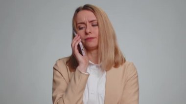 Akıllı telefonda can sıkıcı konuşmalar yapan ilgisiz genç iş kadınının portresi. Uykulu serbest çalışan kadın arkadaşıyla cep telefonundan konuşuyor, gri arka planda çevrimiçi sohbet ediyor.