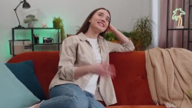 Evdeki kanepede gülümseyen mutlu sakin genç bir kadının portresi. Mutlu bir yüz ifadesi. Başka tarafa bakıyor, hayal kuruyor, rahatlıyor. Oturma odasındaki kanepede oturan kız