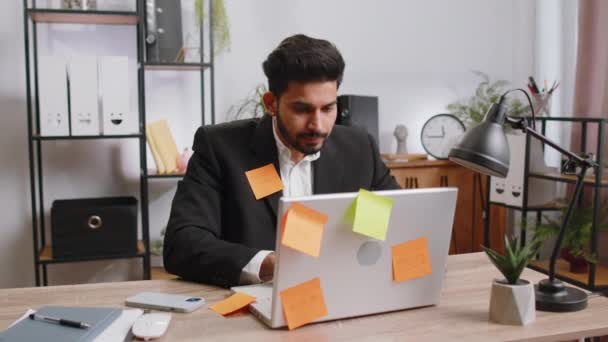 Zmęczony Wyczerpany Indyjski Biznesmen Pracujący Laptopie Biurze Wieloma Naklejkami Napisami — Wideo stockowe