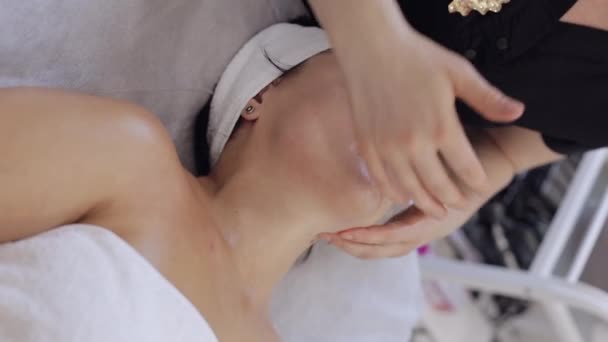 治疗师医生让女人放松 用手按摩温泉脸下巴 美容院提供光滑 健康的护肤治疗 排毒和愈合 面部物理美容术课程的客户 垂直射击 — 图库视频影像