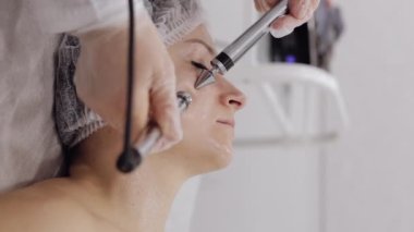 Kırışıklıkları düzeltmek, yenilenmek ve gençleştirmek için kozmetik işlemler için elektrik darbeleri. Klinikteki güzellik uzmanından mikro akım alan orta yaşlı bir kadın.