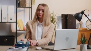 Happy gevşemiş genç iş kadını ev bilgisayarında kulaklık takıp akıllı telefondan favori disko müziğini dinliyor. Serbest çalışan kadın dinleniyor, mola veriyor.