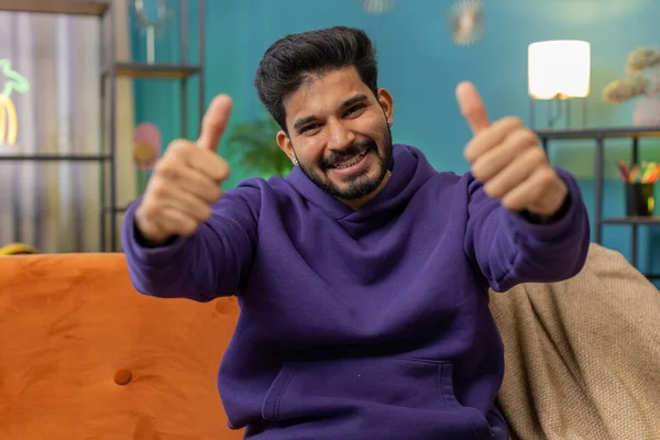 stock image Like. Happy excited indian man looking approvingly at camera showing thumbs up, like sign positive something, good great news, positive feedback. Young hindu guy sitting on couch at home living room