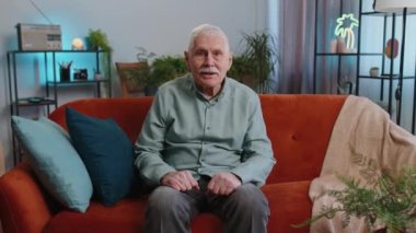 Kanepe oturma odasında heyecanlı büyükbaba. İlginç bir TV oyunu izliyor. Evde sosyal medya içerikli bir film çekiyor. Yaşlı emekli adam eğleniyor.