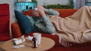Büyükbaba hasta adam soğuk algınlığı ya da alerjiden muzdarip. Evdeki dairedeki kanepede yatıyor. Kafasında havlu olan hasta son sınıf öğrencisi hapşırır, sümüğü peçeteye sürer. Coronavirus karantinası, salgın