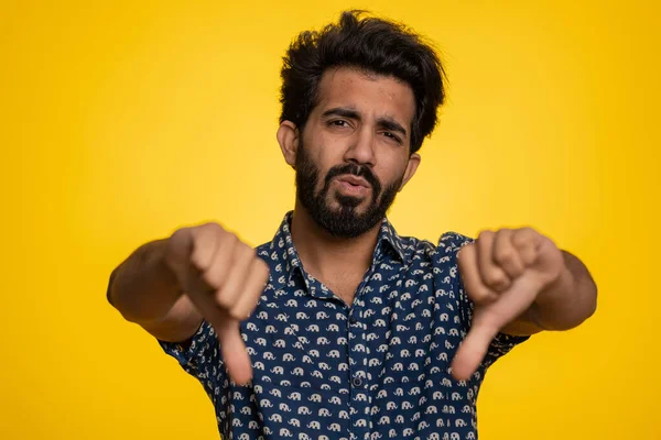 不喜欢 穿着衬衫的不高兴的印地安人露出大拇指垂下的手势 表达不满 不赞成 不满意和不喜欢 英俊的小伙子 黄色背景的室内演播室 — 图库照片