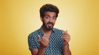 Genç Hintli adam boşa harcıyor, etrafa para saçıyor, daha fazla bahşiş, büyük kar, piyango ikramiyesi, başarılı alışveriş ödemeleri, nakit para. Hintli adam sarı arka planda izole edilmiş.