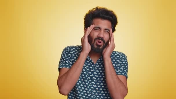 一位英俊的印度大胡子男子穿着衬衫擦拭太阳穴以治疗头痛问题 他患有紧张 高血压等症状 这些症状都是在黄墙背景下单独存在的 — 图库视频影像