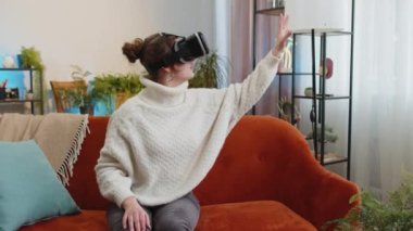 Sanal gerçeklik teknolojisi VR uygulama kulaklığı kullanan bir kadın, video oyunu simülasyonu yapmak için modern ev dairesinde film izliyor. Kanepede gözlüklü bir kız. Büyütme etkisi geçişi