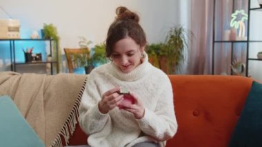 Poor young woman insufficient amount of money, holding piggybank and one dollar banknote at home apartment. Financial crisis. Bankruptcy. Poverty and destitution. Girl in living room sitting on sofa