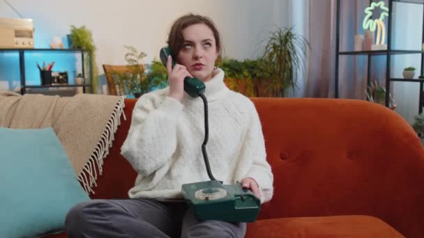 若い疲れ眠い悲しい女性が自宅のアパートでヴィンテージレトロ有線電話で話しています 興味のない不幸な女の子との退屈な会話とともにホットラインヘルプラインサービス座っているソファ — ストック動画