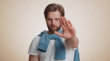 Kızgın adam, dur işaretinde el ele tutuşmak yok diyor. Bitiş uyarısı, giriş yasağı, iletişim kopukluğu, vücut dili, tehlike. Bej arka planda genç bir adam. İnsan yaşam tarzı