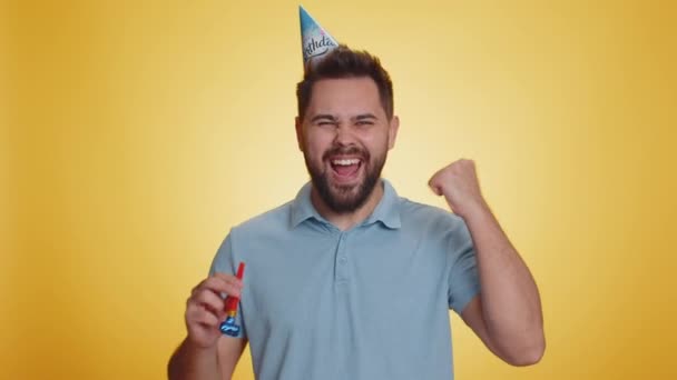 Feliz Joven Con Sombrero Cumpleaños Cone Blow Pipe Celebrando Éxito — Vídeos de Stock