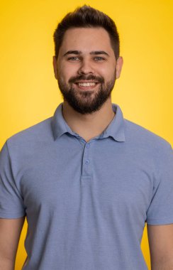 Mutlu, sakin, beyaz bir adamın portresi. Dostça gülümseyen, kameraya bakan, dinlenen, rahatlayan, rahatlayan, iyi haber kutlaması yapan bir adam. Sarı arka plandaki adam. Dikey