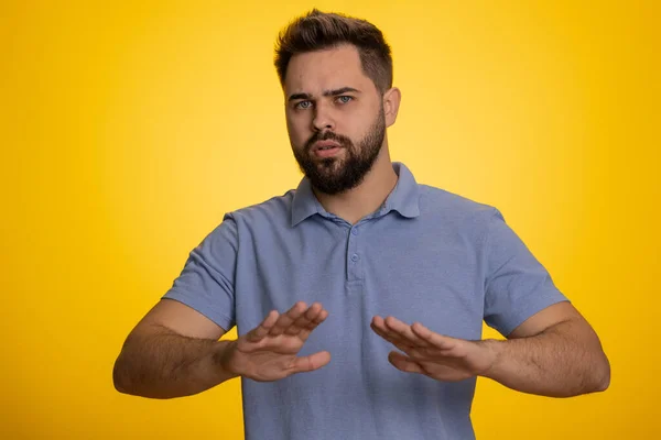 Hey you, be careful. Caucasian man warning with admonishing finger gesture, saying no, be careful, scolding and giving advice to avoid danger, disapproval sign. Guy isolated on yellow background