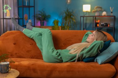 Yorgun genç bir kadın rahat bir kanepeye uzanıp dinleniyor, gündüz uyukluyor. Tasasız genç kızın portresi. Kafasının arkasında el ele tutuşmuş. Rahatlamış, evinde kanepede uyuyakalmış.