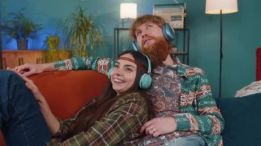 Neşeli genç aile, evdeki kanepede dans eden ve en sevilen disko rock n roll müziğini dinleyen kablosuz kulaklıklı erkek kadınla evli. Karı koca hafta sonu aktiviteleri.