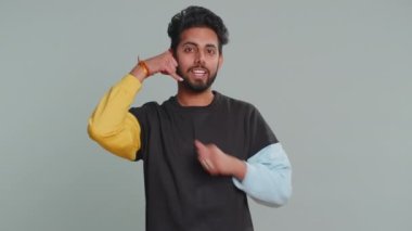 Bizi arayın, bu da iletişim numarası. Süveter giyen yakışıklı sakallı Hintli adam kameraya bakıp 