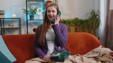 Evdeki kanepede oturan arkadaşlarıyla telgraflı telefon konuşması yapan genç bir kadının portresi. Mutlu heyecanlı kız 90 'lı yıllardan kalma eski moda telefonlardan keyif alıyor.