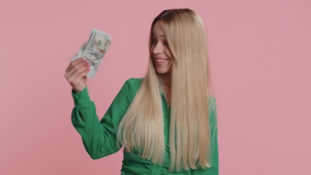 有钱的老板高兴地看着女人挥动钞票 像扇子一样的钞票 成功的商业生涯 彩票中奖 丰厚的收入 漂亮的高加索女孩在粉红的背景上被隔离在室内 — 图库视频影像