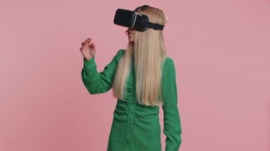 Gerçekçi simülasyon oyunları oynamak için kulaklık uygulaması kullanan beyaz bir kadın. Sanal gerçeklik 3D 360 videosu izliyoruz. Sanal gerçeklik gözlüklü genç kız aygıtı pembe arka planda, kapalı alanda izole edilmiş.