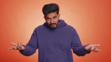 Neden? Öfkeli bir ifadeyle el kaldıran samimi, asabi Hintli adam başarısızlığının nedenini sorar. Tehlikenin huzursuzluğunu gösterir. Turuncu arka planda kafası karışmış yakışıklı Hintli adam.