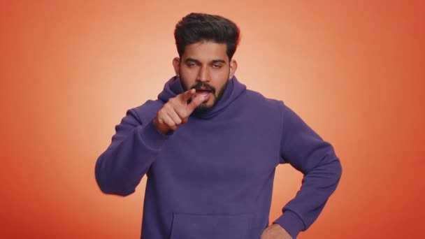 愤怒的印度年轻人模仿刀 用手指表现出割喉的致命动作 在室内橙色工作室背景下被割断的手脖子 — 图库视频影像