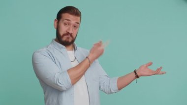 Lübnanlı genç adam onaylıyor ve boş bir yeri işaret ediyor. Ticari metinler için reklam alanı, ürün tanıtımı için kopyalama alanı. Sakallı Arap adam mavi stüdyo arka planında, kapalı alanda izole edilmiş.