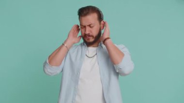 Duymak ve dinlemek istemiyorum. Sinirli sinirli Lübnanlı adam kulaklarını kapatıyor. Hayır, nahoş sesleri görmezden gelerek tavsiyelerden kaçınıyor. Mavi arka planda tek başına yakışıklı bir Arap.