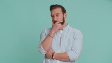 Sinsi kurnaz Lübnanlı sakallı adam hileli yüzüyle şeytani planlar yapıyor sinsi hain fikirleri, kurnaz hileleri, şakaları, eşek şakalarını düşünüyor. Mavi arka planda izole edilmiş bir Arap.