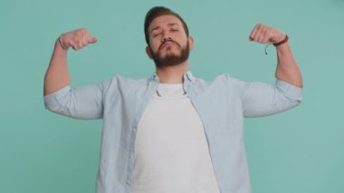 Güçlüyüm. Formda Lübnanlı adam kaslarını gösteriyor ve kendinden emin görünüyor. Başarılı olmak için hak enerjisi için savaşacak gücü hissediyor. Arap adam kapalı alanda mavi arka planda izole edilmiş.