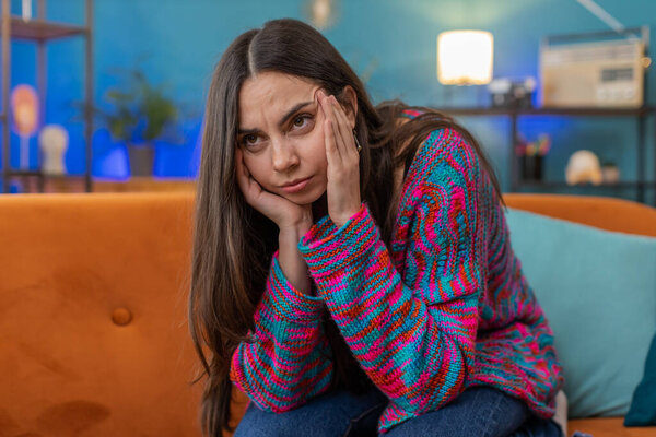 Displeased woman rubbing temples to cure headache problem, suffering from tension and migraine, stress grimacing in pain high blood pressure at home room apartment. Caucasian girl on couch. Lifestyles