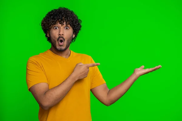 年轻的印地安人竖起大拇指 指着空旷的地方 商业广告区 复制商品促销空间 有胡子的后生家伙 隔离在绿色色调的背景下 在室内 — 图库照片