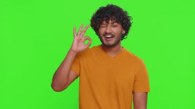 Tamam, tişörtlü neşeli mutlu Hintli adam kameraya olumlu bir geri bildirim hareketi göstererek olumlu bir işaret veriyor. Krom anahtar altyapısı olan yakışıklı bir adam. İnsanlar samimi duygular