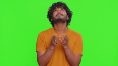 Lütfen, Tanrım yardım et, beni affet. Hintli adam dua ediyor, yukarı bakıyor ve dilek tutuyor, umutlu bir ifadeyle soruyor, özür diliyor. Yeşil krom anahtar arka planında izole edilmiş yakışıklı Hindu adam.