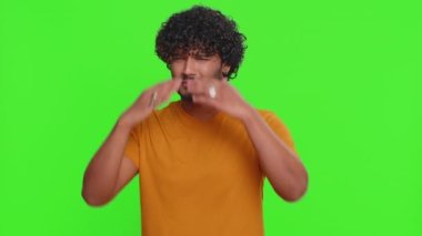 Buna bakmak istemiyorum, çok kötü. Korkmuş Hintli yakışıklı adam gözlerini kapatıyor. Durma hareketi gösteriyor. Kafası karışmış, utangaç, izlemekten korkuyor. Genç adam krom anahtar arka planında izole edilmiş. İnsan yaşam tarzları