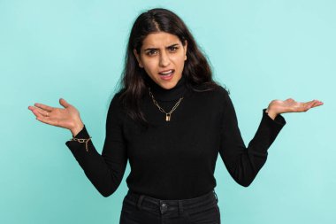 Neden? Öfkeli bir ifadeyle el kaldıran samimi, rahatsız edici Hintli kadın başarısızlığının nedenini sorar. Tehlikenin huzursuzluğunu gösterir. Mavi arka planda kafası karışmış bir Hintli kız.