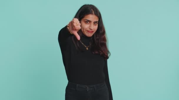 嫌いだ セーターで親指を看板ジェスチャーを示す不幸なインド人女性を動揺 嫌いな表現 若い娘だ 屋内撮影所青の背景 — ストック動画