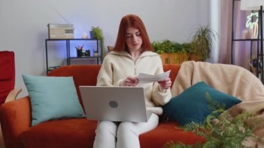 Stresli bir kadın, bankanın ödenmemiş borçlarına bakıyor, evrak işleriyle uğraşıyor, bütçe planlıyor, mortgage ödemelerini hesaplıyor. Kızıl saçlı kız kanepeye kağıt para atıyor. Yaşam Tarzları