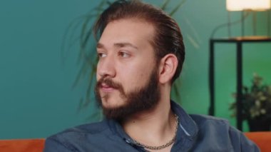 Mutlu, sakin Lübnanlı bir adamın portresi. Kanepede gülümseyen, mutlu, mutlu bir yüz ifadesi. Başka tarafa bakıyor, hayal kuruyor, rahatlıyor. Oturma odasındaki Arap adam.