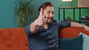 Gibi. Mutlu, heyecanlı Lübnanlı adam kameraya olumlu bakıyor, olumlu bir işaret veriyor, iyi haber olumlu geri bildirim gibi. Oturma odasındaki kanepede oturan genç bir Arap.