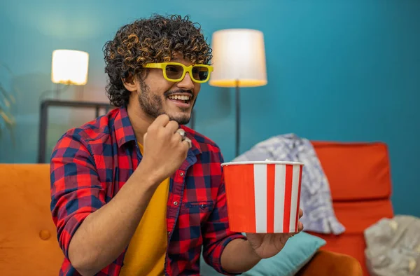 身穿3D眼镜的兴奋的印度人坐在沙发上吃爆米花零食 在家里看有趣的电视连续剧 在线社交媒体电影内容 喜欢娱乐的人 — 图库照片