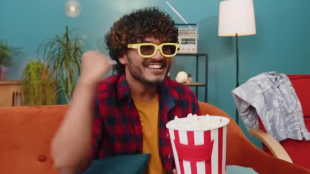 Podekscytowany Indianin Okularach Siedzi Kanapie Jedząc Popcorn Przekąski Oglądając Ciekawe — Wideo stockowe