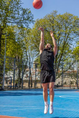 Spor giyim sektöründe sporcu Lübnanlı bir adam basketbol oynarken basket ringine topu başarıyla attı. Şehir merkezindeki yaz mahkemesinde genç bir adam. Spor sahasında spor rutini. Motivasyon. Açık havada.