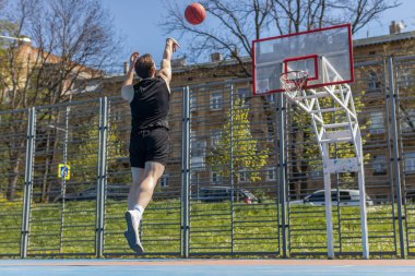 Spor giyim sektöründe sporcu Lübnanlı bir adam basketbol oynarken basket ringine topu başarıyla attı. Şehir merkezindeki yaz mahkemesinde genç bir adam. Spor sahasında spor rutini. Motivasyon. Açık havada.