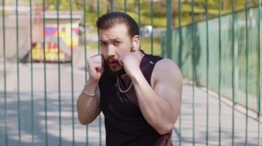 Spor giyimli atletik Lübnanlı adam gölge boksu aerobik kardiyografisi eğitimi alıyor. Çocuk parkındaki Orta Doğulu genç adam. Rutin çalışma. Güç ve motivasyon. Açık spor salonu.