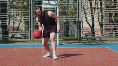 Spor giyim sektöründe basketbol oynayan Lübnanlı bir sporcu. Şehir kortunda top süren genç adam topa vuruyor. Spor sahasında spor rutini. Egzersiz, egzersiz, antrenman. Güneşli bir sabahta açık havada