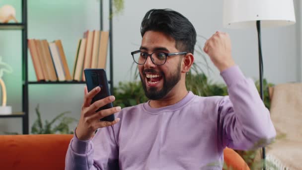 Счастливый Индиец Скрестив Пальцы Использовать Мобильный Смартфон Просмотра Говорят Вау — стоковое видео