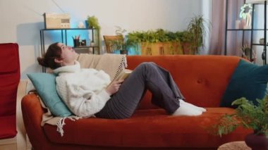 Repair work at neighbours. Irritated woman girl relaxing on couch cover ears with pillows annoyed by noisy neighbors suffer from headache wish silence. Thin walls at home flat without sound insulation