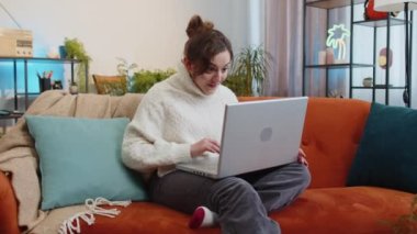 Aman Tanrım. Vay canına. Laptop bilgisayarı kullanan genç bir kadın, iyi haber mesajı alıyor, ani zaferi kutluyor piyango galibiyetini evde online alışveriş yaparak kutluyor. Yaşam tarzı teknolojileri